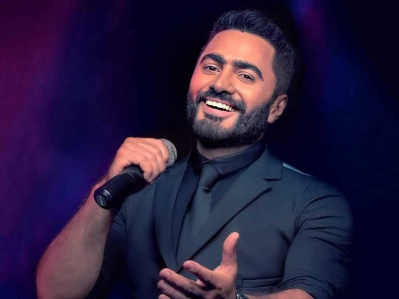 Tamer Hosny Jeddah Season concert: singing live on purple background